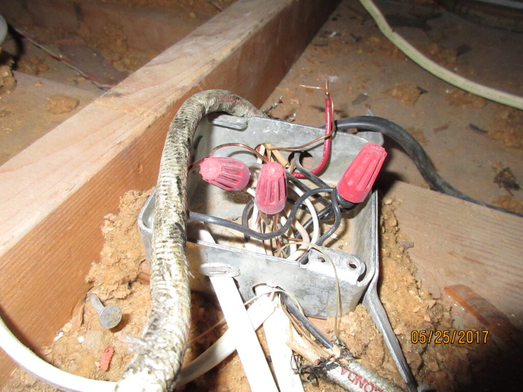 Photo of exposed electrical wiring inside an attic.